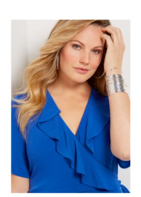 Model in black blazer with lace detail, pastel purple top, & black pants. 